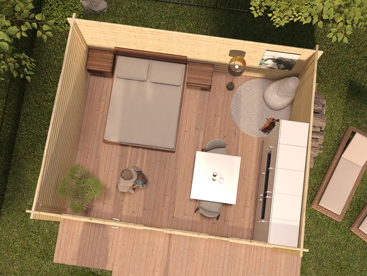 Draufsicht auf ein eingerichtetes Gartenhaus aus Holz mit Doppelbett, Esstisch, großem Schrank und Stehlampe auf hellem Dielenboden.