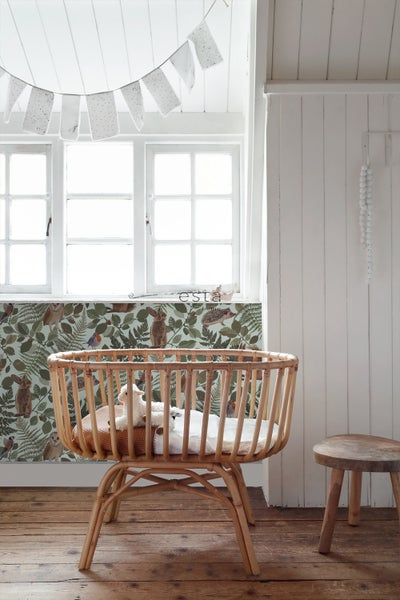 Helles Kinderzimmer mit Rattanwiege, Fenster und gemusterter Tapete