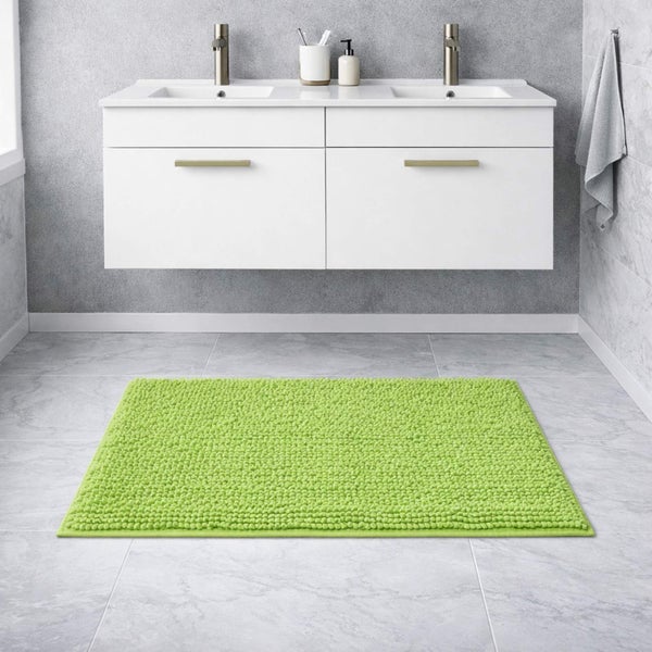Grüner strukturierter Badteppich in einem Badezimmer mit weißem Doppelwaschtisch, zwei Waschbecken, silbernen Armaturen und grauen Bodenfliesen.