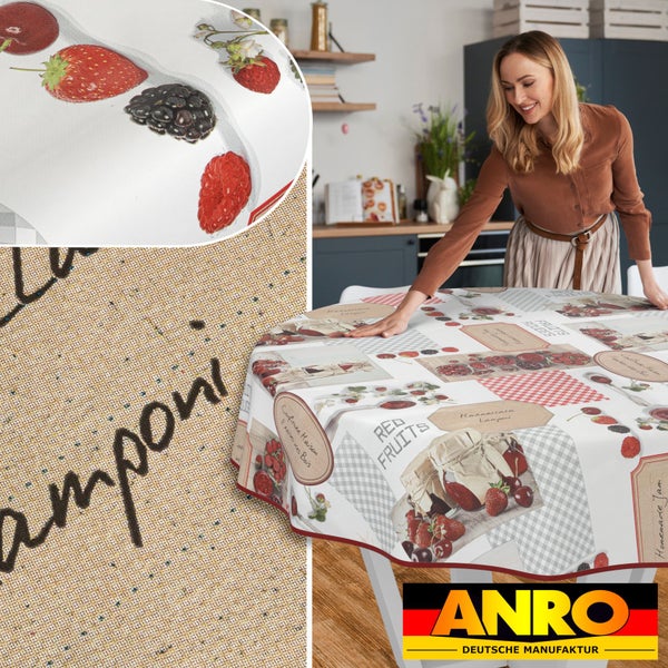 Frau deckt runden Esstisch mit Wachstuchdecke mit Früchtedekor