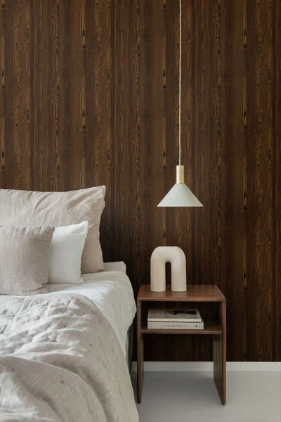 Schlafzimmer mit Wand in Holzoptik Tapete hinter einem Bett mit Nachttisch und Pendelleuchte in einem modernen und wohnlichen Stil.