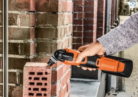 Handgeführter Akku Multifunktionswerkzeug mit Starlock Plus Aufnahme beim Einsatz an einem Backstein.