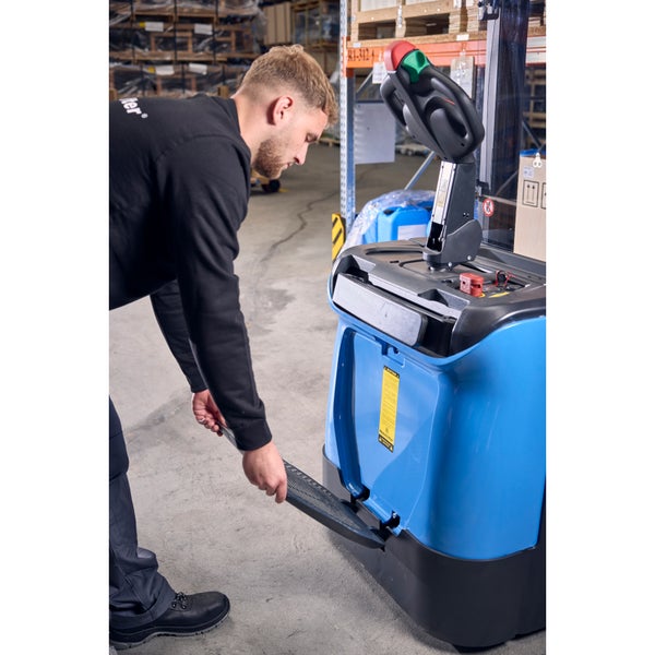 Ein Mitarbeiter öffnet die Einstiegsstufe eines Kommissionierers in einem Lager.