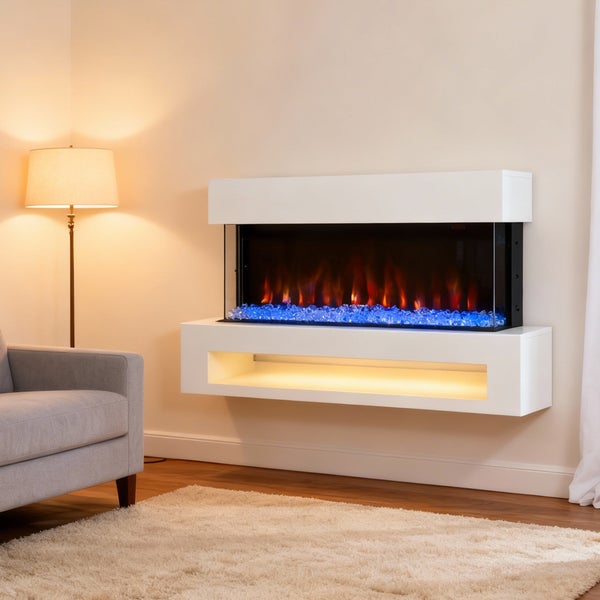 Moderner wandhängender Elektrokamin in Weiß mit Flammen-Effekt und blauen Dekosteinen in einem hellen Wohnzimmer mit Sessel und Stehlampe.