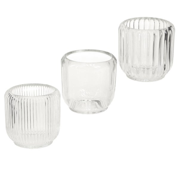 Drei Teelichthalter aus Glas, zwei mit vertikaler Rillenstruktur und einer mit glatter Oberfläche.
