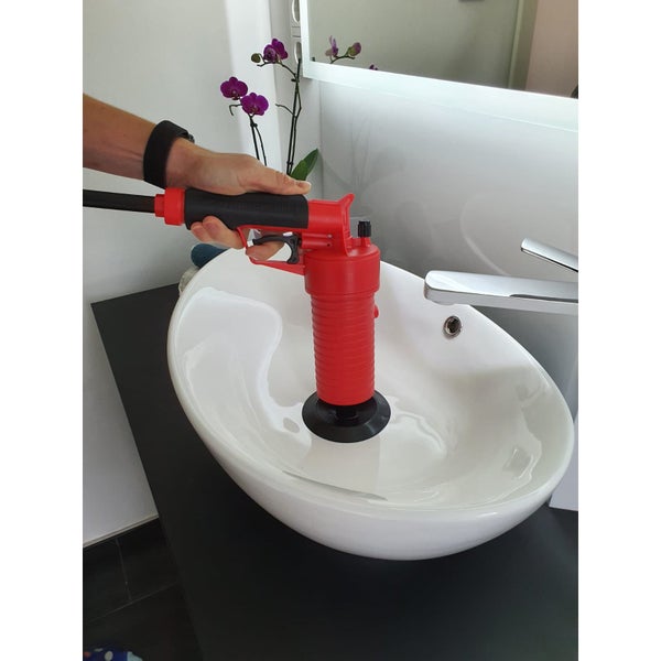 Eine Hand bedient einen Rohrreiniger über einem Waschbecken