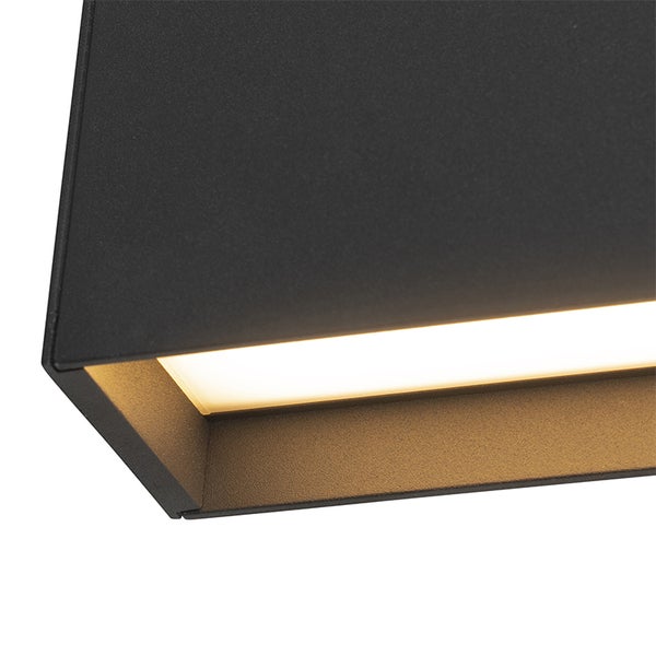 Detailaufnahme einer schwarzen, strukturierten Wandleuchte mit warmweißem LED-Lichtschein.