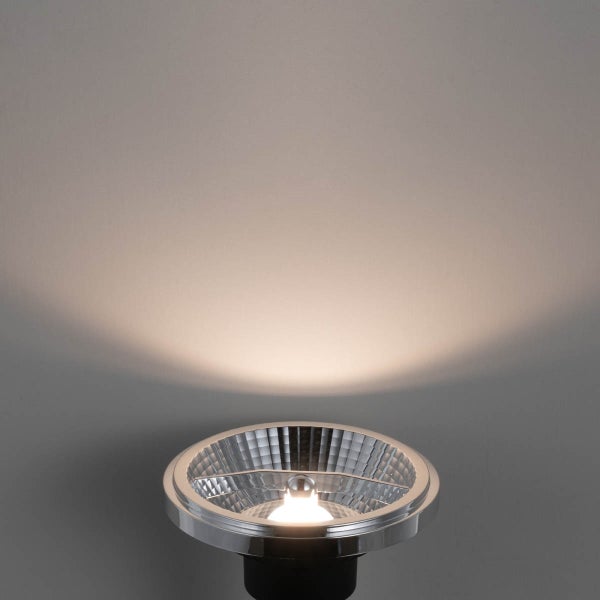 LED-Strahler mit facettiertem Reflektor, der warmweißes Licht auf eine Fläche strahlt.