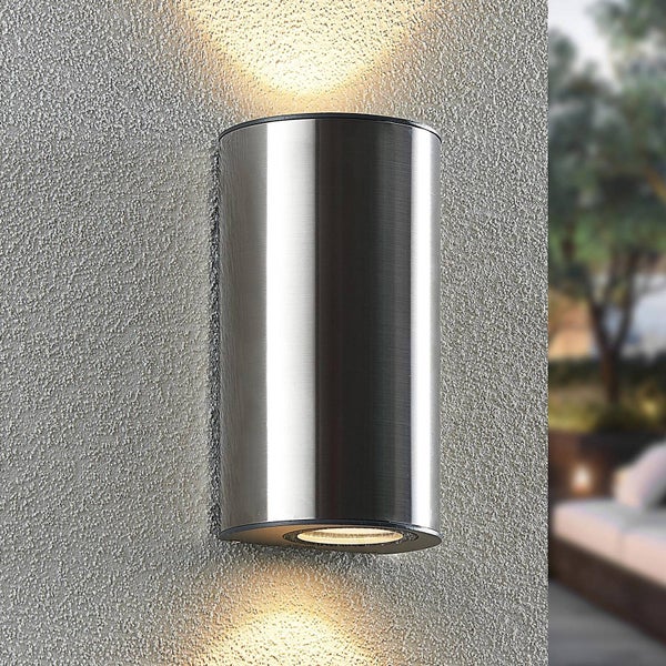 Zylindrische Wandaußenleuchte aus gebürstetem Edelstahl mit Lichtaustritt nach oben und unten an einer strukturierten Wand.