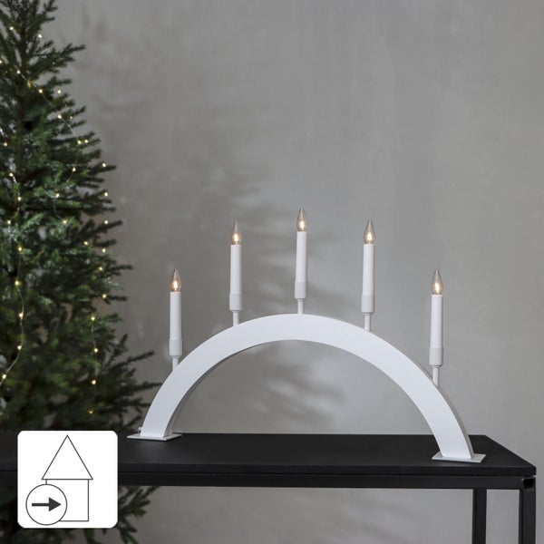 Weihnachtsleuchter mit fünf Lichtern auf einem Tisch neben einem Weihnachtsbaum