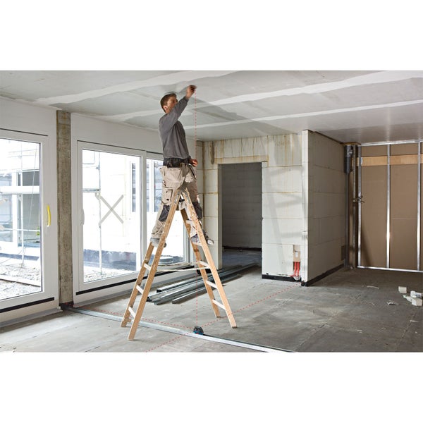 Handwerker auf Holzleiter im Rohbau mit Laser zur Ausrichtung von Decke und Boden