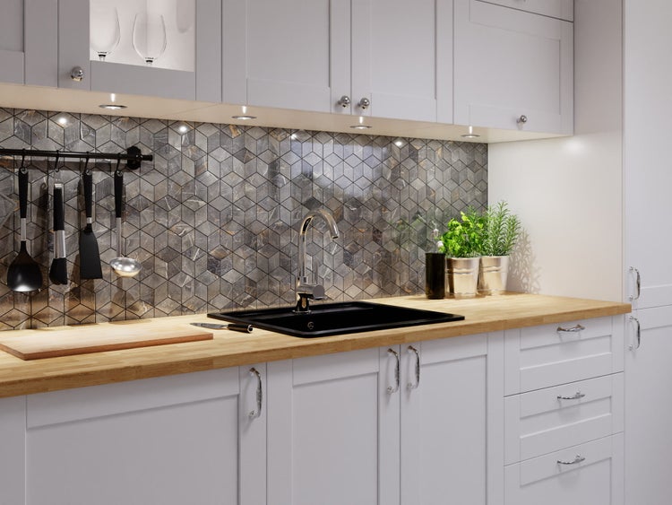 Moderne Einbauküche mit weißer Front, Arbeitsplatte in Holzoptik, schwarzem Spülbecken und Fliesenspiegel aus grauen Mosaikfliesen in Hexagonform.