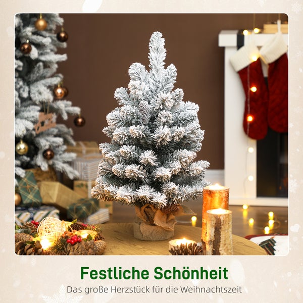 Künstlicher Mini-Weihnachtsbaum mit Schneeeffekt, Tannenzapfen und Jutesockel in einem hellen Raum mit Adventskranz und Kerzen.