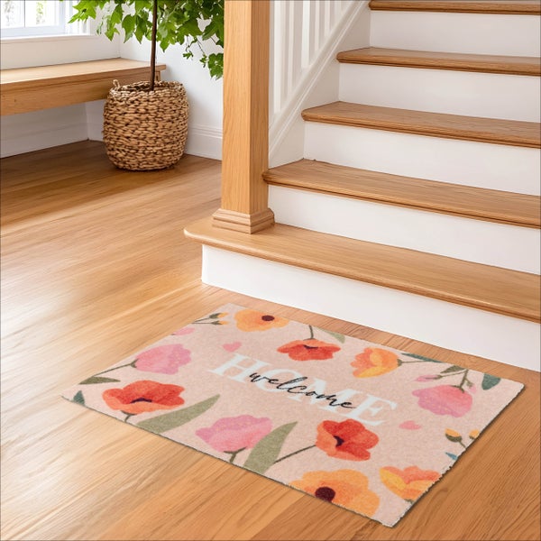 Rechteckige Fußmatte mit Blumenmuster und Schriftzug HOME welcome auf hellem Holzboden vor einer Treppe in einem hellen Eingangsbereich.