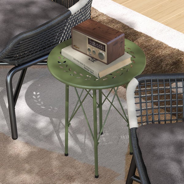 Grüner runder Metallbeistelltisch mit Blattmuster-Ausstanzungen, platziert zwischen zwei modernen Gartensesseln auf einem Außenteppich.