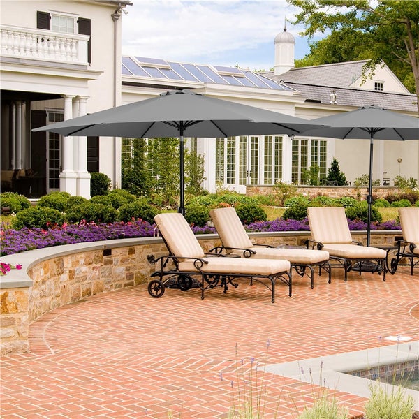 Szene mit mehreren Liegestühlen unter Sonnenschirmen im Gartenbereich eines Hauses.