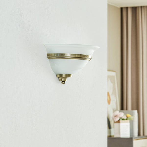 Halbschalen-Wandleuchte mit satiniertem Glasschirm und dekorativen Metallringen in Altmessing-Optik.