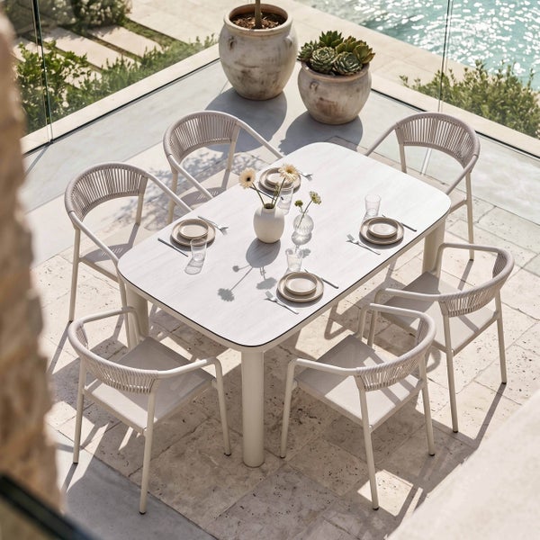 Moderne Garten-Essgruppe auf einer sonnigen Terrasse mit einem hellen rechteckigen Tisch und sechs Stühlen mit Seilgeflecht-Rückenlehne.