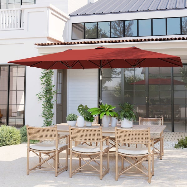 Großer, rechteckiger Sonnenschirm in Rot über einem Esstisch mit geflochtenen Stühlen auf einer hellen Terrasse vor einem modernen Haus.