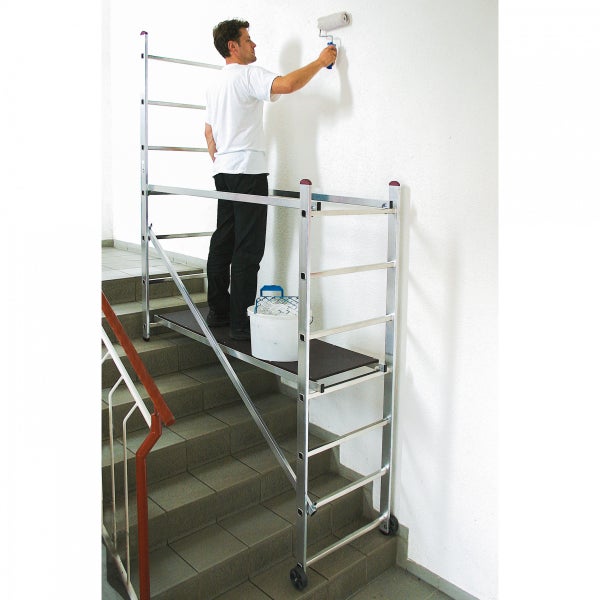 Mann streicht Wand von einem Gerüst auf einer Treppe aus