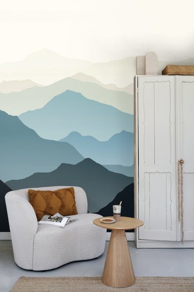 Wohnzimmer mit Bergtapete, Sessel, Beistelltisch und Schrank für eine gemütliche Atmosphäre