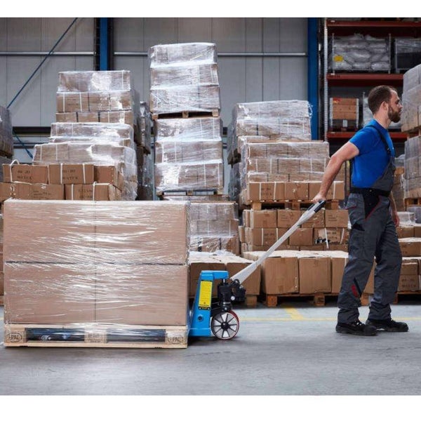 Ein Mann zieht einen blauen Hubwagen mit einer beladenen Palette durch ein organisiertes Lagerhaus