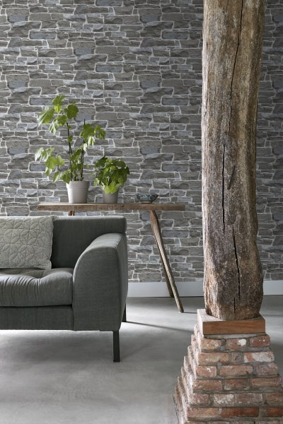 Wohnzimmer mit Steintapete, Sofa und Holzsäule für ein rustikales Ambiente