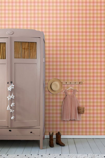 Kinderzimmer mit karierter Tapete in Rosa und Ocker, historischer Kleiderschrank aus Holz, Wandgarderobe mit Kinderkleid und Strohhut.