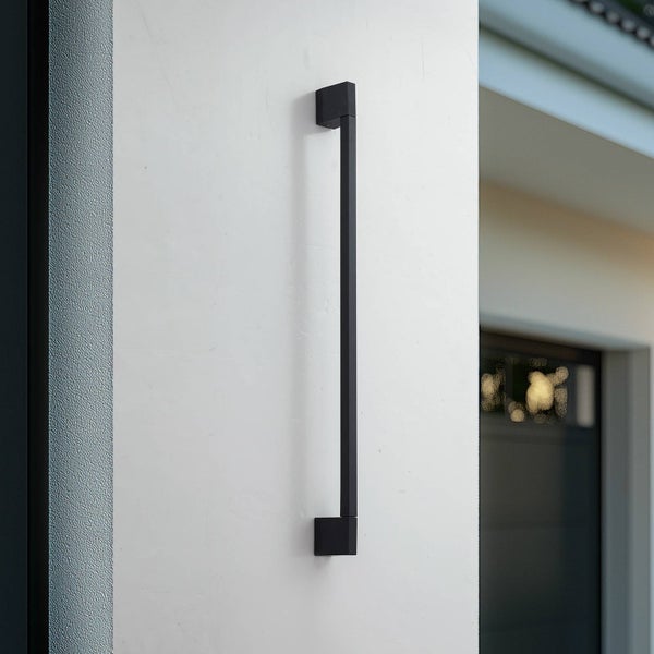 Moderne schwarze Außenwandleuchte in langer, schmaler Rechteckform, vertikal an einer Hauswand montiert.