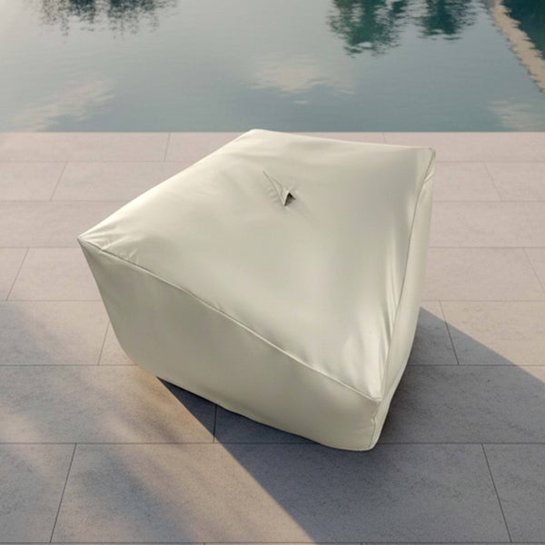 Quadratischer Outdoor Sitzsack in Beige auf einer hellen Terrasse aus Steinplatten neben einem Pool.