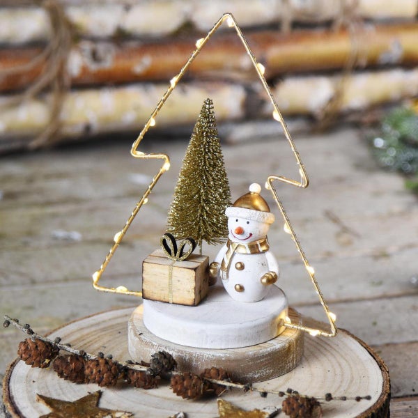 Dekorative Weihnachtsszene mit Schneemann, Geschenk und Weihnachtsbaum unter einem beleuchteten Baum