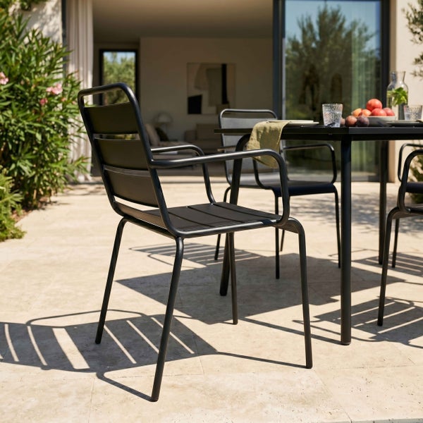 Moderner schwarzer Gartenstuhl aus Metall mit Armlehnen und Latten-Design auf einer sonnigen Steinterrasse.