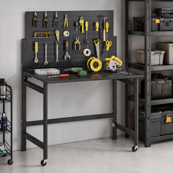 Mobile Werkbank aus Metall mit Lochwand und Werkzeug neben einem Lagerregal in einer organisierten hellen Werkstatt.