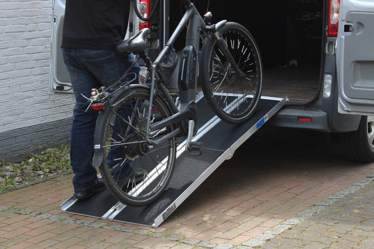 Fahrrad wird über eine Auffahrrampe in einen Transporter geschoben.