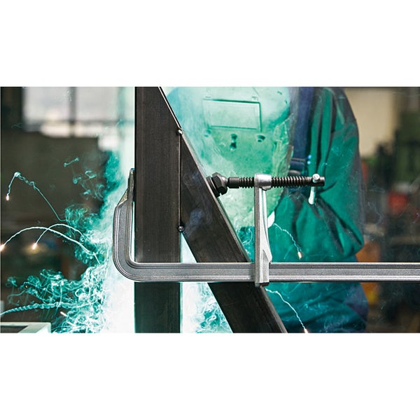 Schweißer bei der Arbeit mit einer Schraubzwinge zum Fixieren von Metall