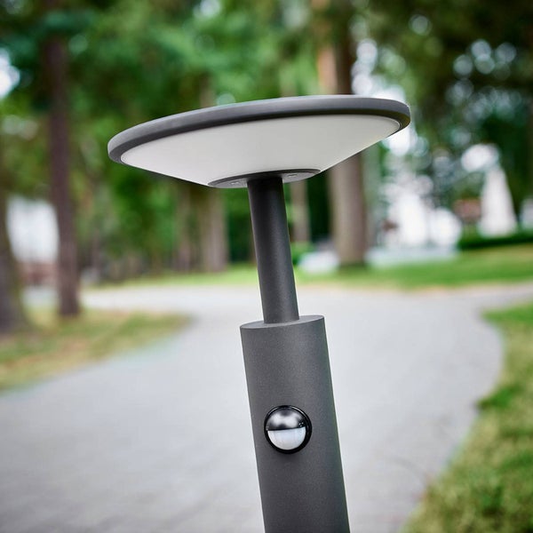 Moderne LED-Wegeleuchte in Anthrazit mit integriertem Bewegungsmelder an einem Gartenweg.