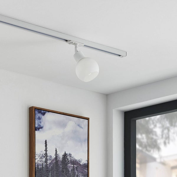 Moderner weißer Schienensystem-Strahler in Kugelform an der Decke montiert in einem hellen Raum neben einem Wandbild.