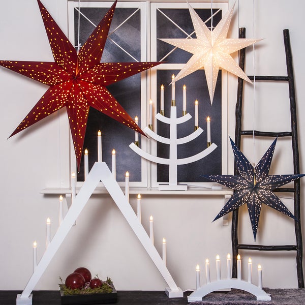 Dekorative Szene mit beleuchteten Sternen und Kerzenleuchtern vor einem Fenster und einer Leiter