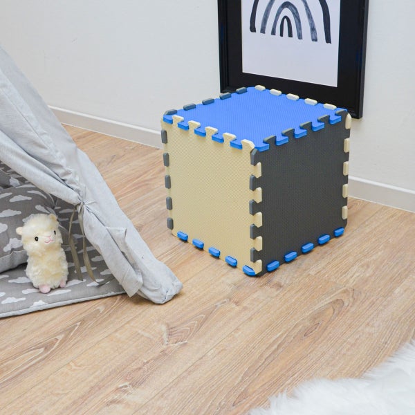 Zu einem Würfel zusammengesteckte Schaumstoff-Puzzlematten in einem Kinderzimmer neben einem Spielzelt auf Boden in Holzoptik.