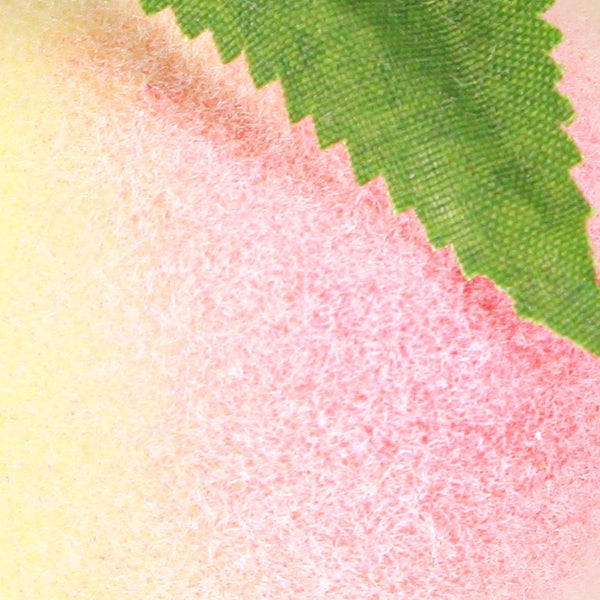 Detailaufnahme einer künstlichen Pfirsichfrucht mit Blatt