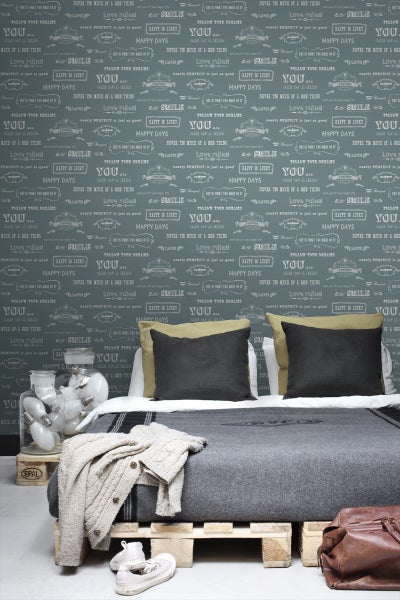 Schlafzimmer mit Bett auf Paletten und beschrifteter Tapete