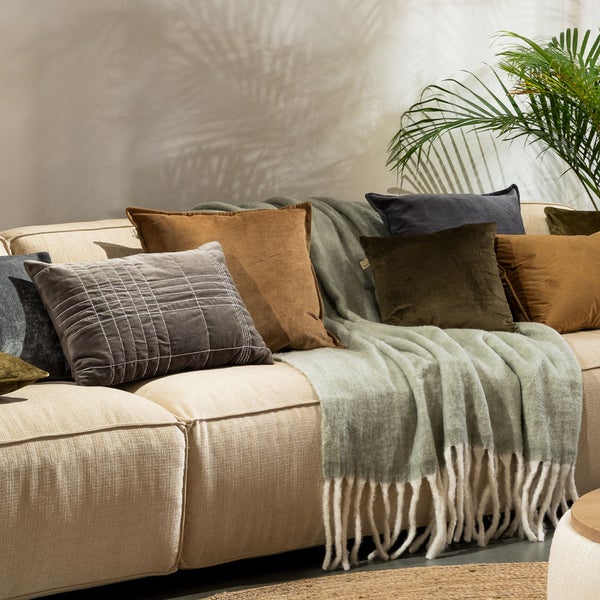 Wohnzimmer-Szene mit Sofa, Kissen und Decke für eine gemütliche Atmosphäre