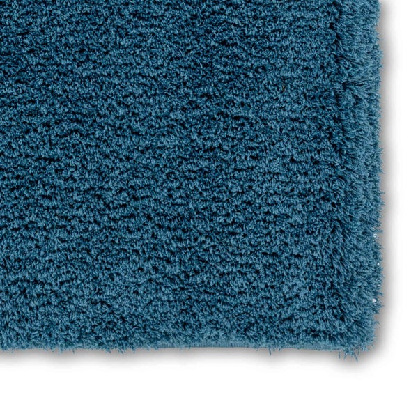 Nahaufnahme eines blauen, hochflorigen Badeteppichs mit zotteliger Struktur.