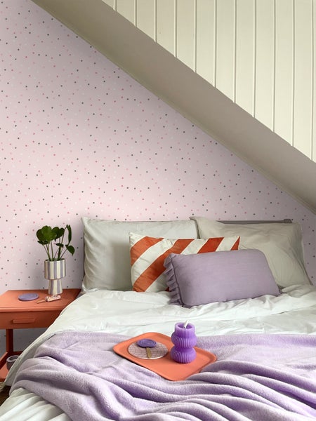 Helles Schlafzimmer mit Bett, Kissen und Nachttisch unter einer Dachschräge