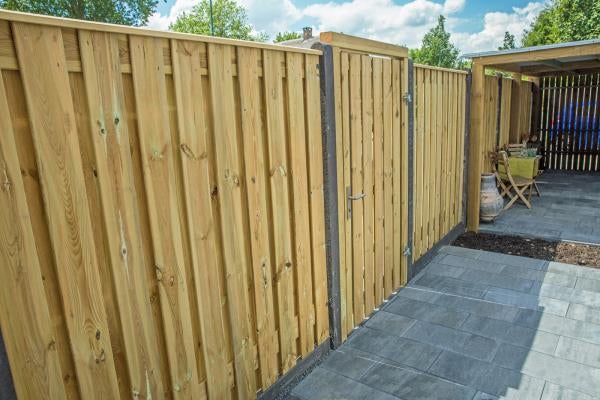 Holzzaun mit Gartenpforte und vertikalen Holzlatten auf einer hellen, gepflasterten Terrasse.