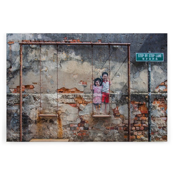 Wandbild mit Street Art Motiv von zwei Kindern auf einer Schaukel vor einer alten Backsteinmauer und Straßenschild Step By Step Lane