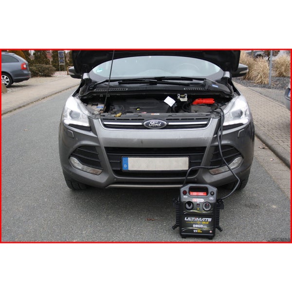 Eine Person mit Arbeitshandschuhen hantiert mit einem Werkzeug unter der Motorhaube eines Autos.