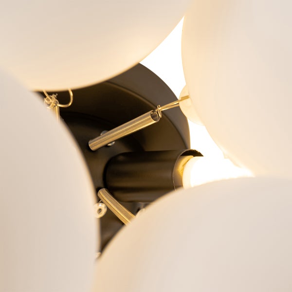 Detailaufnahme einer Deckenleuchte mit matten Kugelschirmen, Federn und Lampenfassung