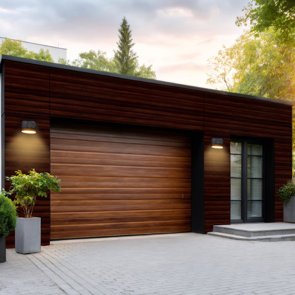 Modernes Garagengebäude mit Holztor und Außenbeleuchtung.