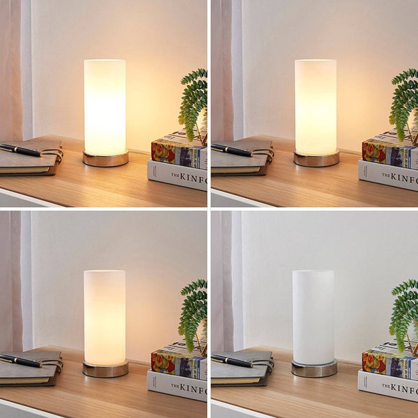 Zylindrische Tischleuchte mit Metallfuß auf einem Holzschreibtisch in vier Helligkeitsstufen von hell bis ausgeschaltet.